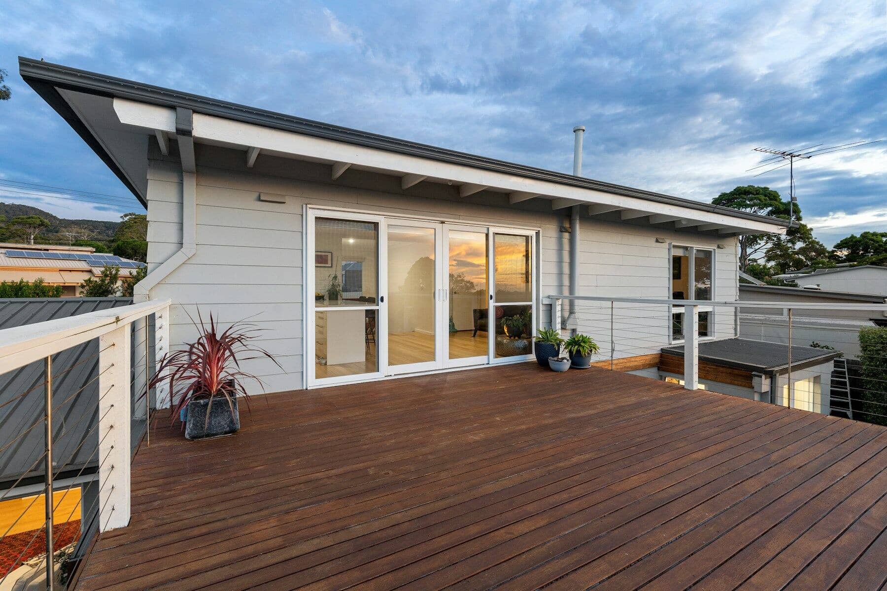 Small modern weatherboard dwelling with sliding doors opening onto a timber deck